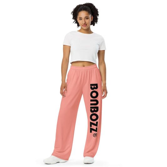 Unisex-Hose mit weiten Beinen und Allover-Druck N°0, rosa, elastischer Bund, stylisch und bequem, modelliert von einer Person in weißem Top.