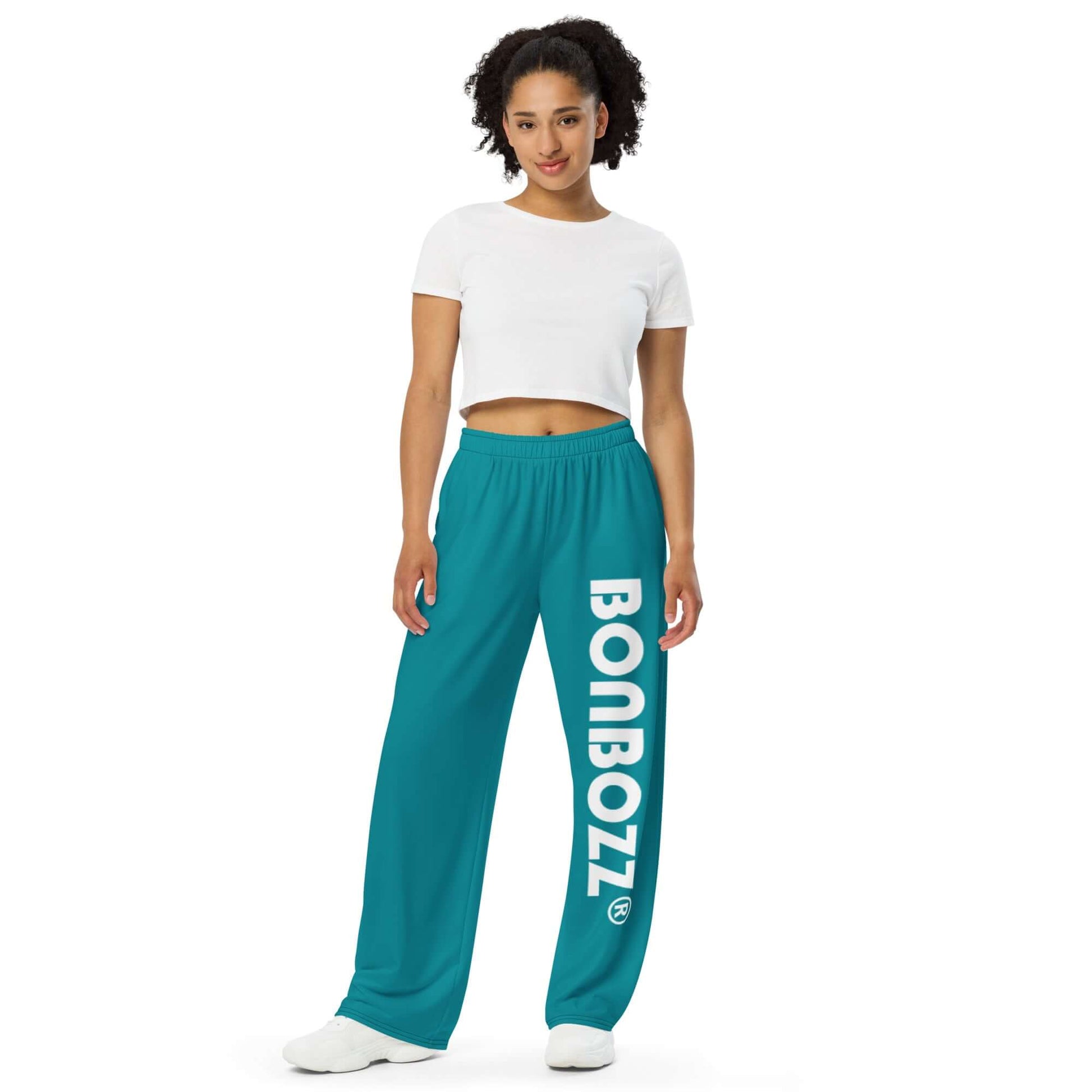 Model wearing Unisex-Hose mit weiten Beinen und Allover-Druck N°4, featuring a turquoise color and bold BONBOZZ text on the leg.