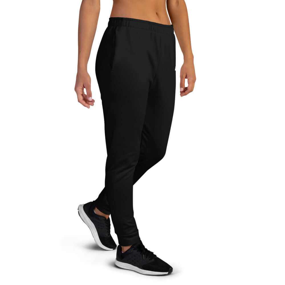 Person wearing black Damen-Jogginghose N°1 showing side view with cuffed legs and athletic shoes