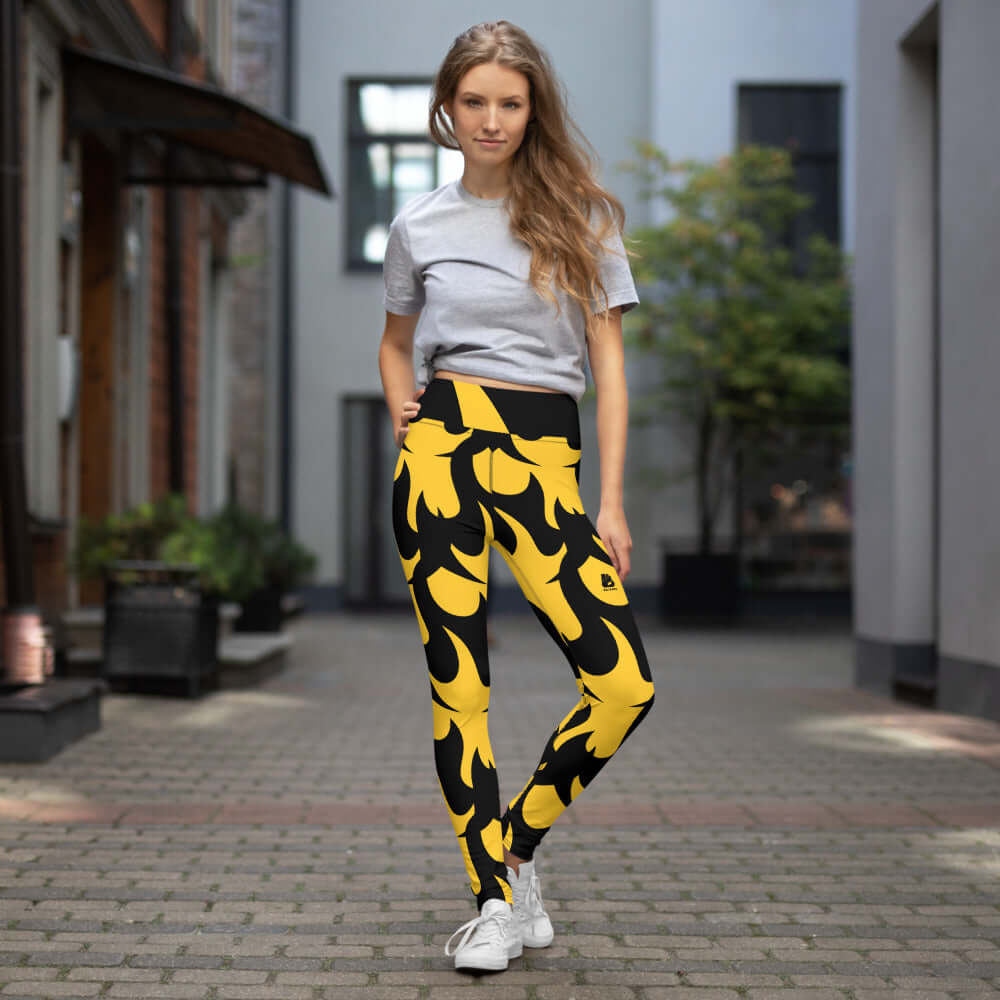 Woman wearing stylish yellow flame graphic Yoga-Leggings N°1 showcasing stretch and comfort in an urban setting.