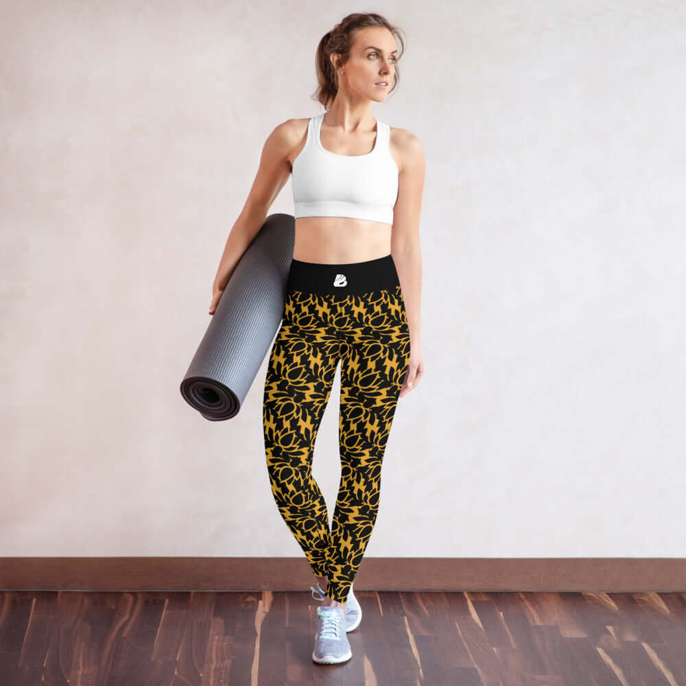 Woman wearing Yoga-Leggings N°22 with a yoga mat, showcasing black and yellow stretchy leggings in a studio setting.