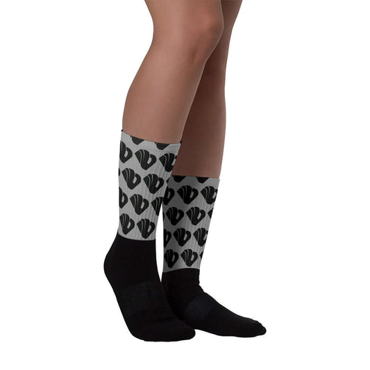 Person wearing Socken N°8 with black foot and colorful patterned leg, featuring cushioned sole and ribbed leg. Available in various sizes.