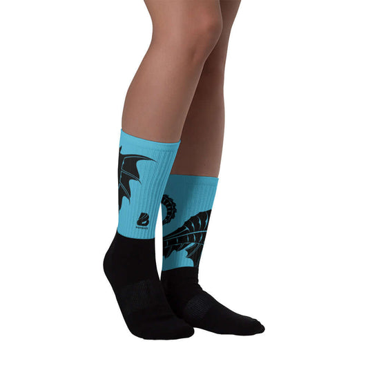 Person wearing Socken N°9 with black foot and vibrant design on blue leg, featuring cushioned soles and ribbed pattern. Fashion and comfort.