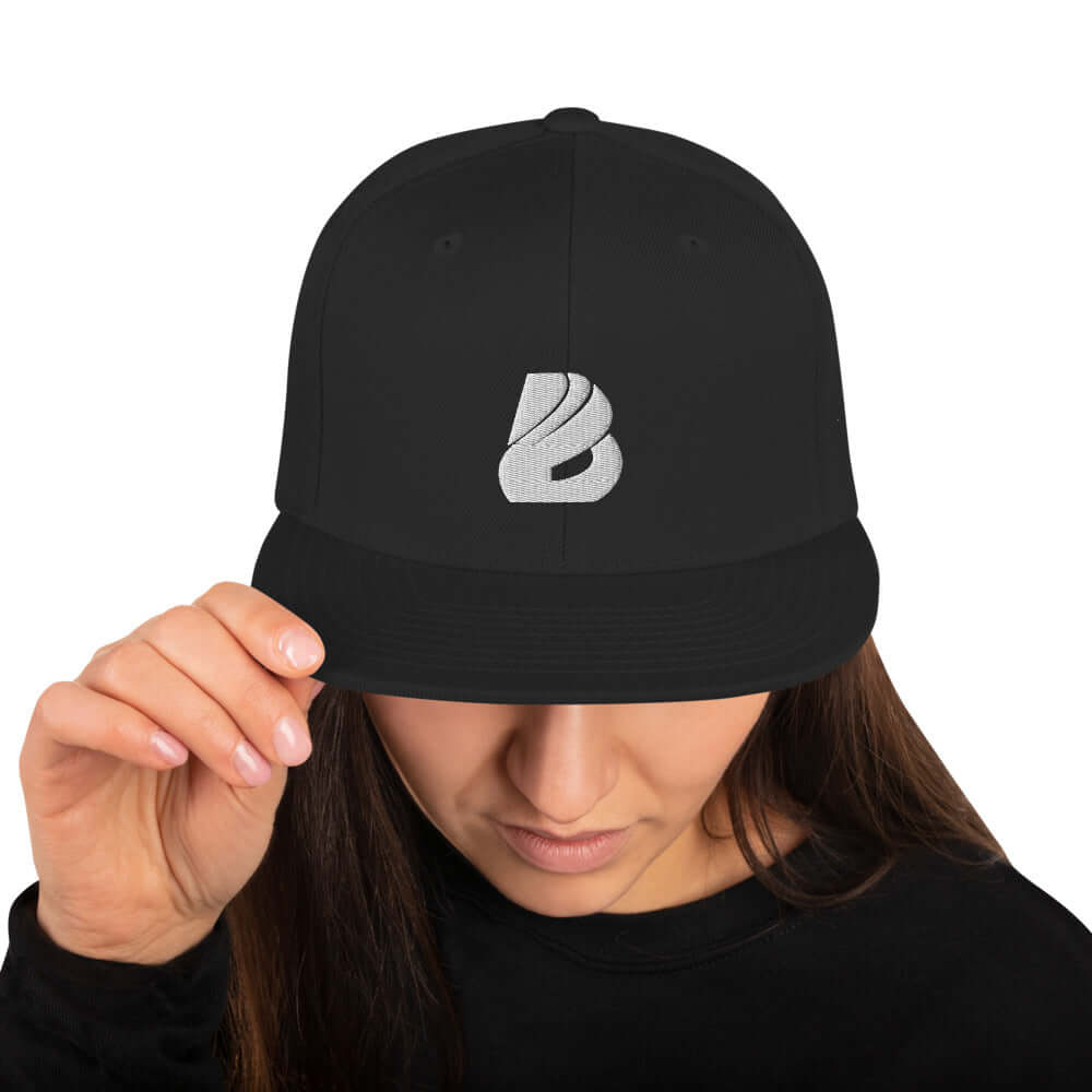 Woman wearing Snapback-Cap N°1 with a structured high-profile and flat visor, featuring a unique embroidered logo on the front.