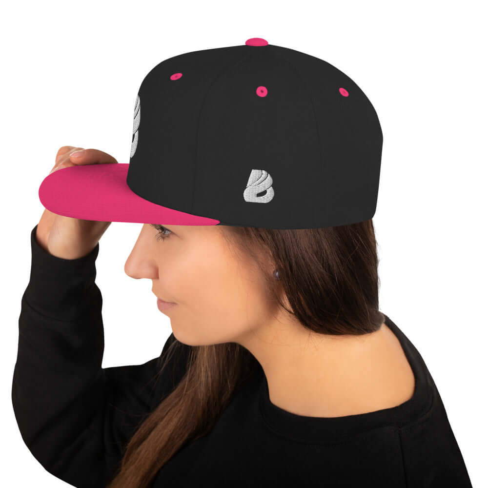 Woman wearing Snapback-Cap N°1 with black and pink design, featuring flat brim and adjustable snap closure.