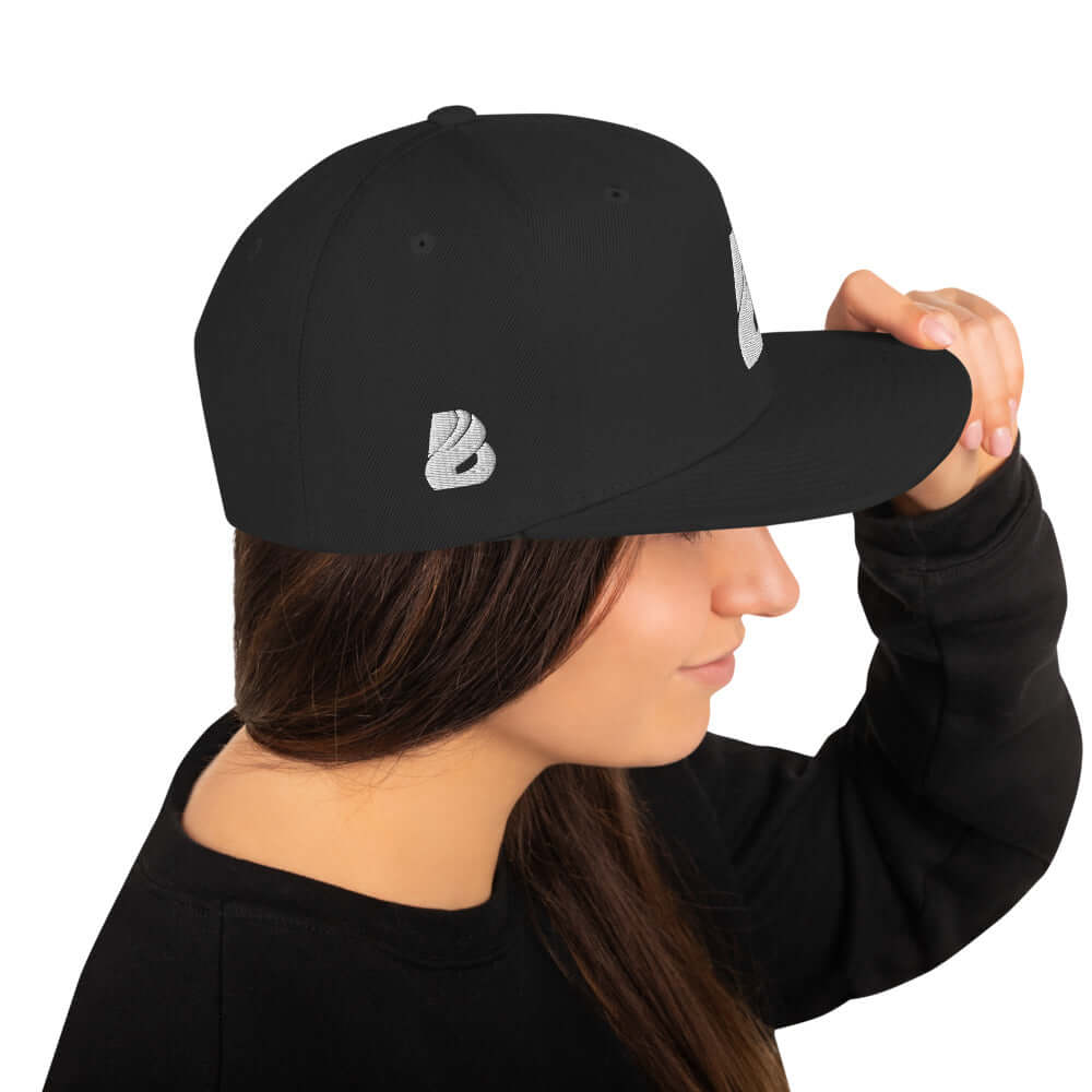 Woman wearing black Snapback-Cap N°1 with structured, high-profile design and adjustable snap closure.