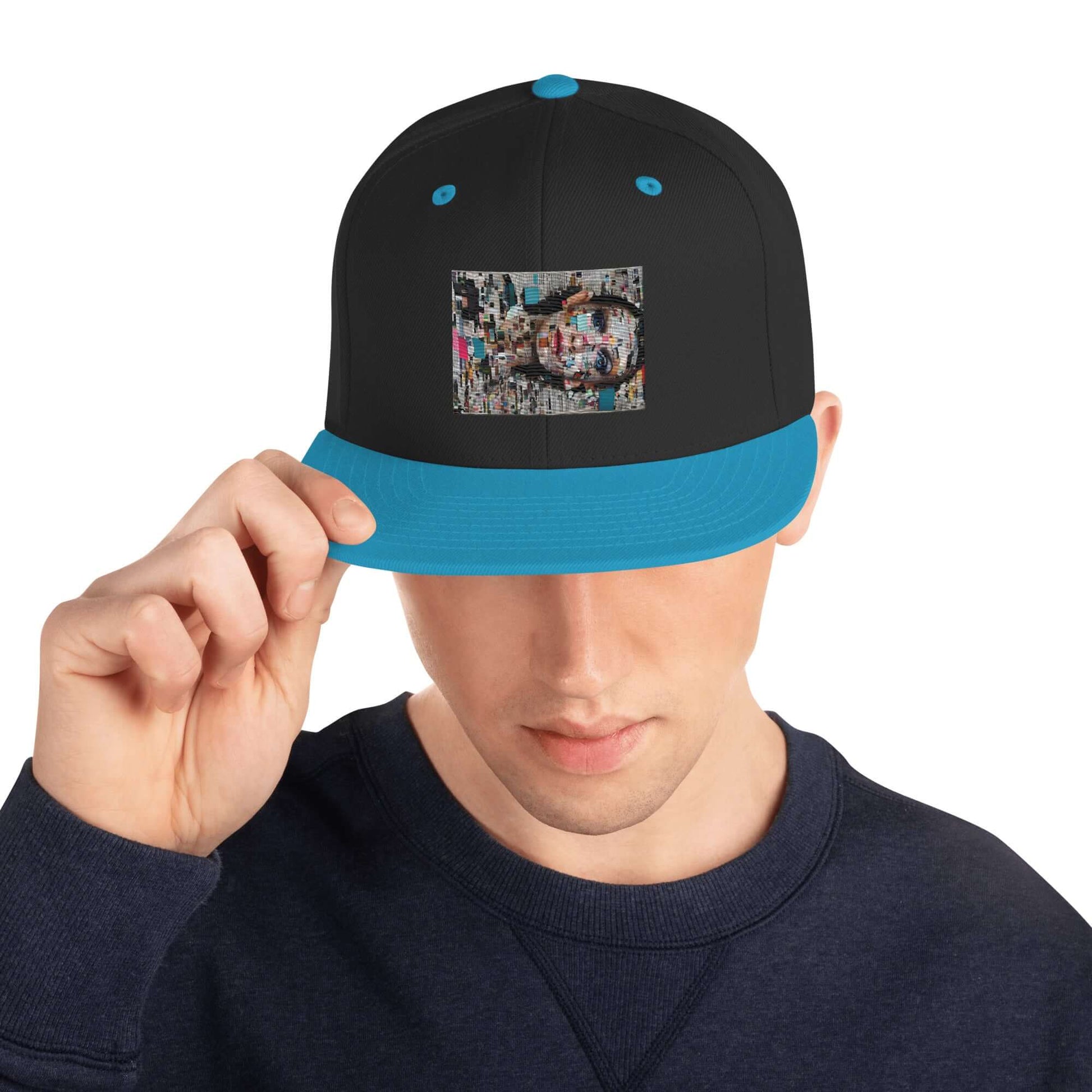 Snapback-Cap N°6 in black with blue brim, classic fit, flat visor, adjustable snap closure, worn by a model in a blue sweater