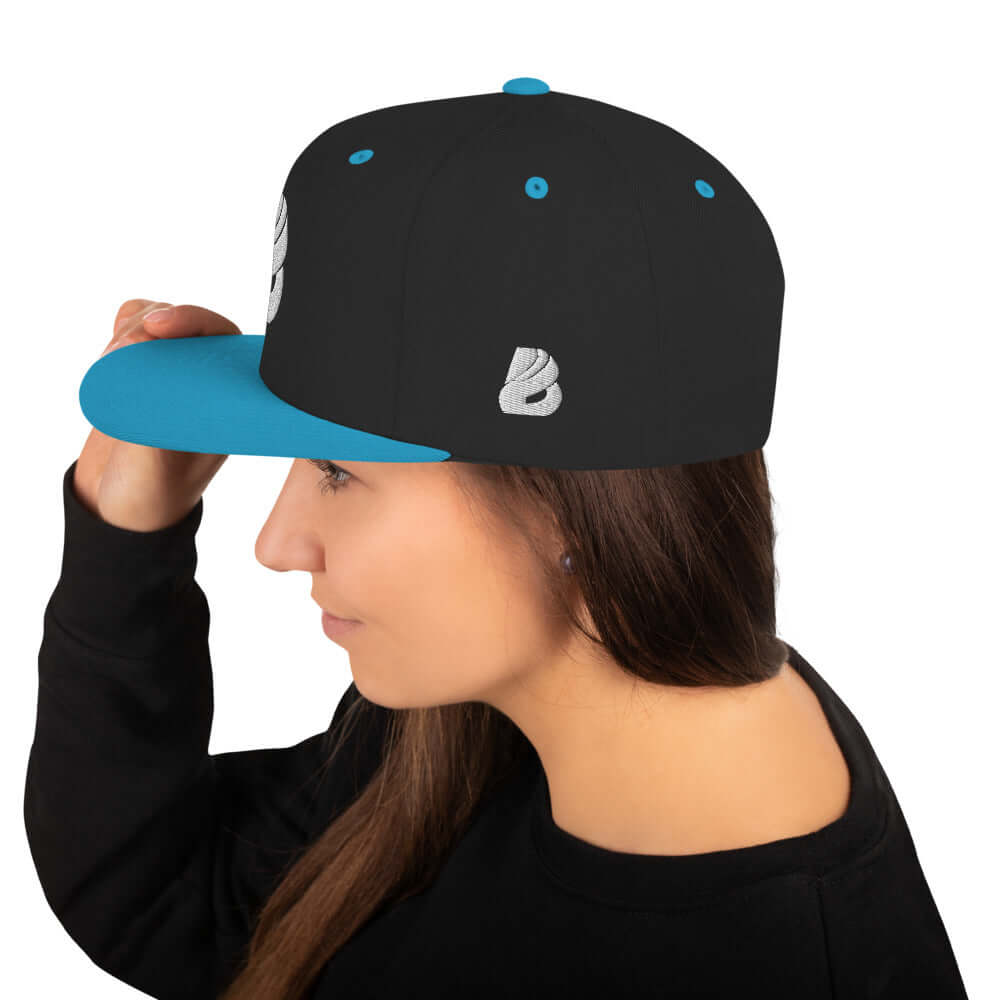 A woman wearing Snapback-Cap N°1 with a flat brim and adjustable snap closure, featuring a high-profile design and blue accents.