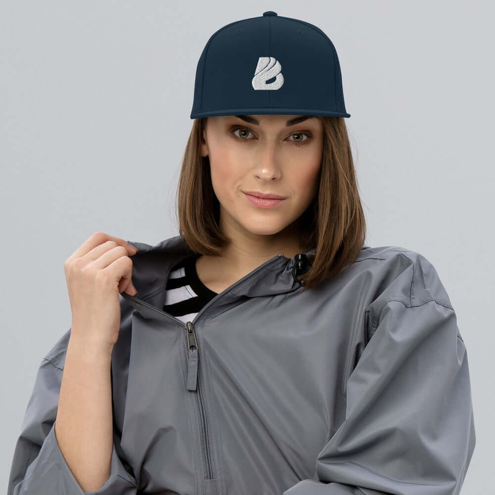 Woman wearing Snapback-Cap N°1 with classic fit and flat brim, styled with a grey jacket.