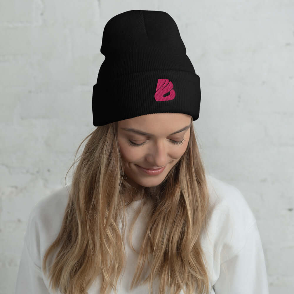 Woman wearing black Umgeschlagene Beanie N°1, showcasing stylish, warm, and hypoallergenic design with pink logo detail.