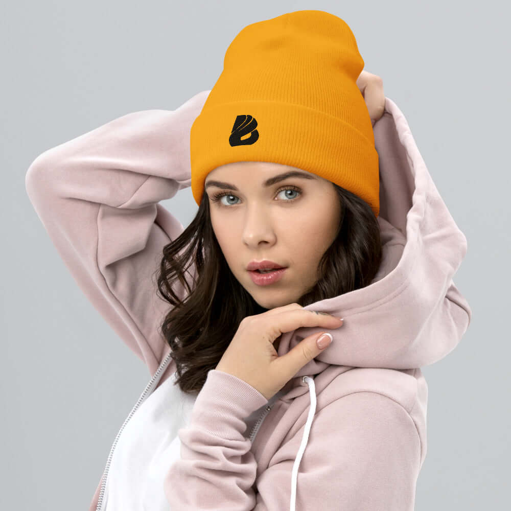 Model wearing orange Umgeschlagene Beanie N°0 with folded cuff and logo, showcasing its snug fit and style.