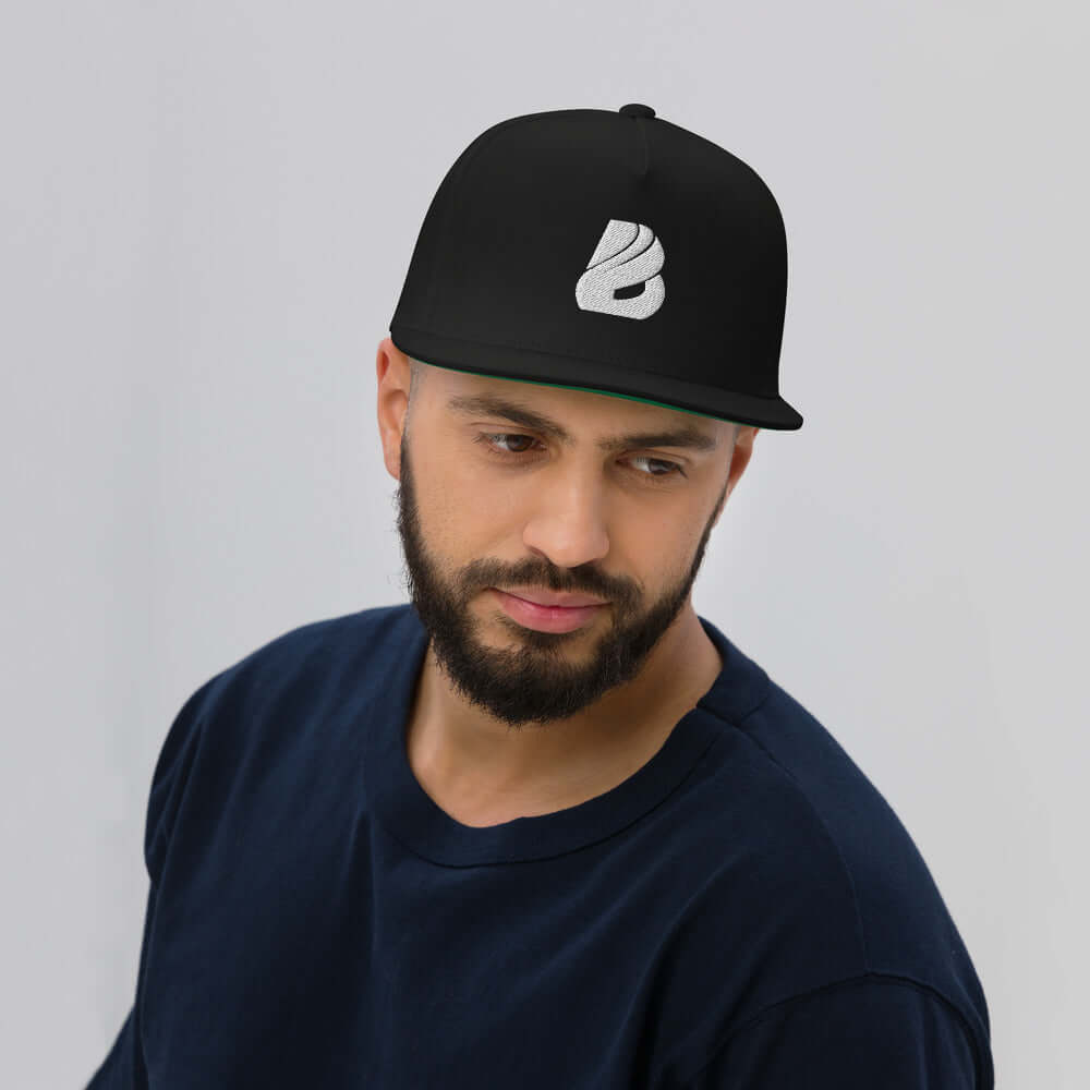 Flat Bill-Cap N°1 in black worn by a man, featuring a green under visor and snapback closure, made from 100% cotton cord.