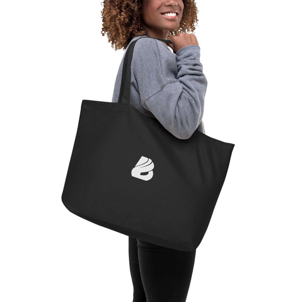 Woman carrying Großer Bio-Baumwollbeutel N°0, a large black organic cotton tote bag with white logo