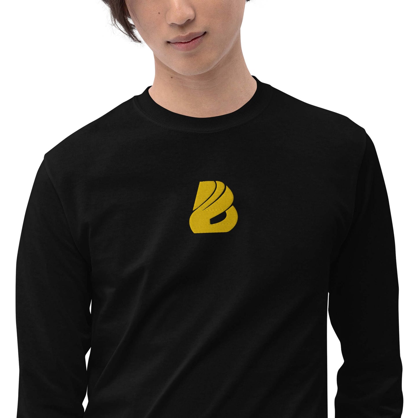 Model wearing Herren-Langarmshirt N°2 with ribbed cuffs and classic fit, featuring a yellow logo on black fabric, perfect for cool days.