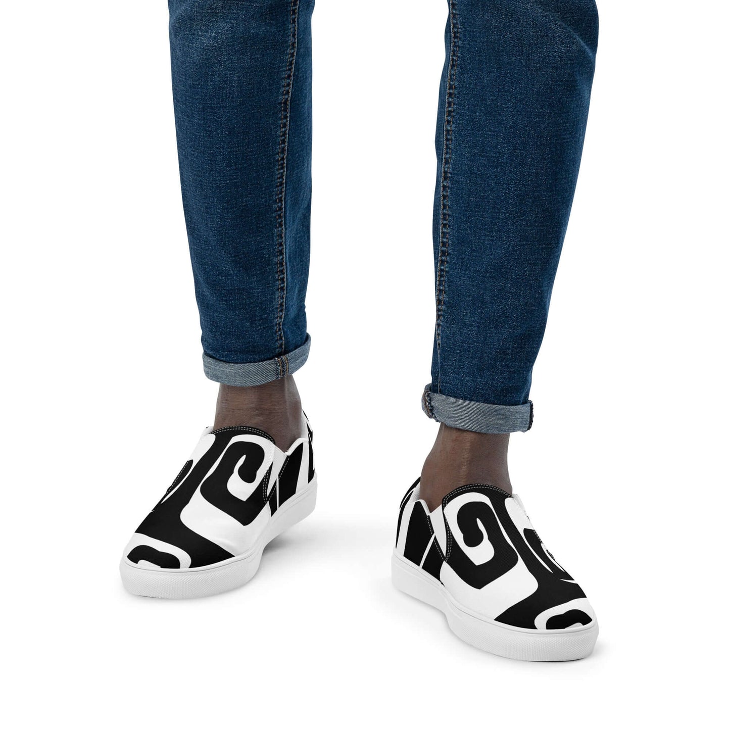 Person wearing Herren-Canvas-Slipper N°0 with black and white swirl design, showcasing comfort and style with denim jeans.