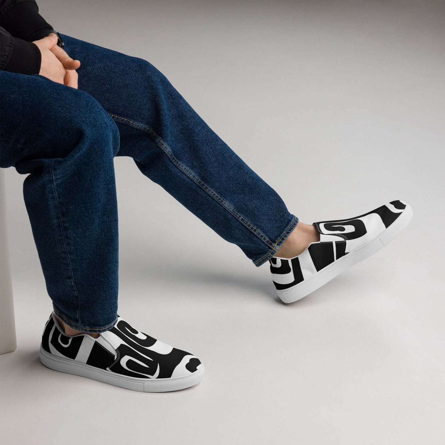 Person wearing Herren-Canvas-Slipper N°0 with patterned design, seated casually, showcasing comfort and style.