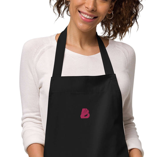 Woman wearing Schürze aus Bio-Baumwolle N°0, black organic cotton apron with front pocket and adjustable straps, ideal for cooking.