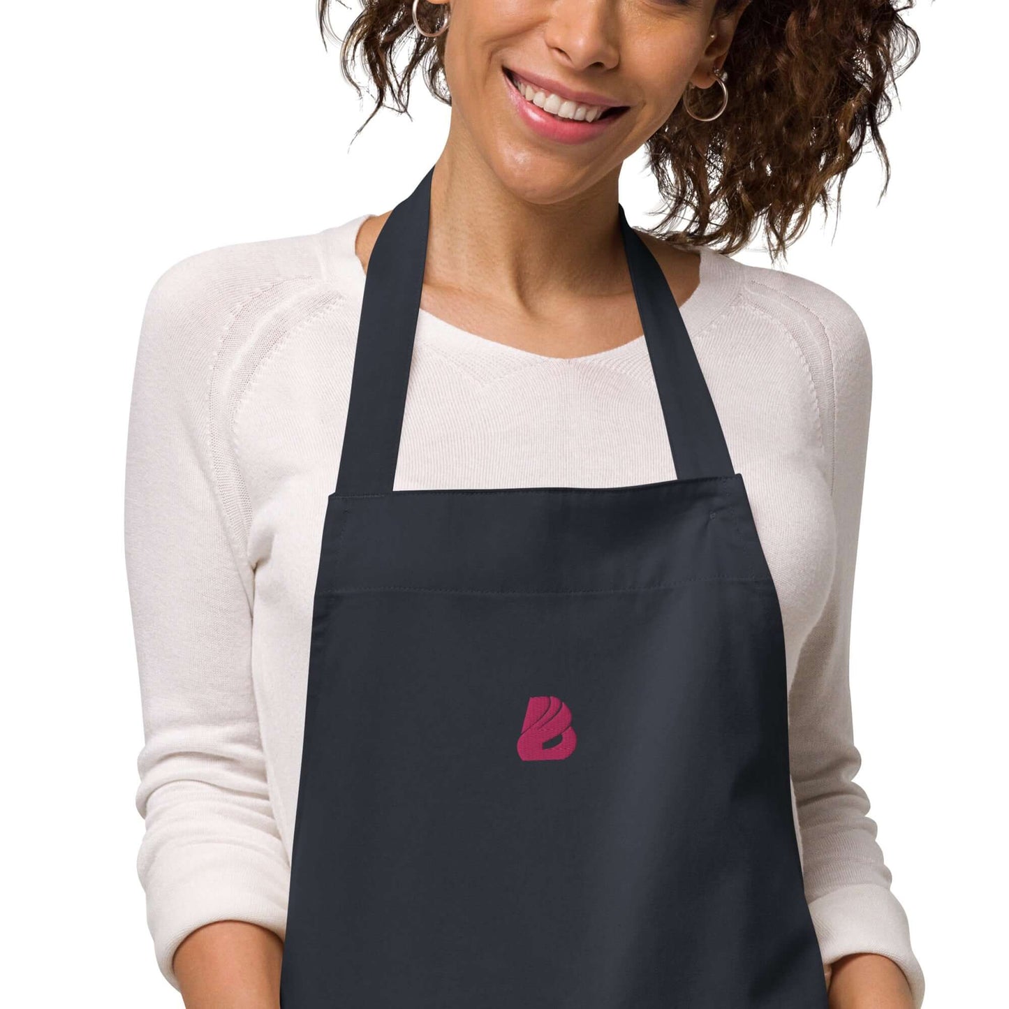 Frau trägt Schürze aus Bio-Baumwolle N°0 mit verstellbaren Bändern, ideal zum Kochen. Elegante Bio-Schürze schützt vor Küche Schmutz.