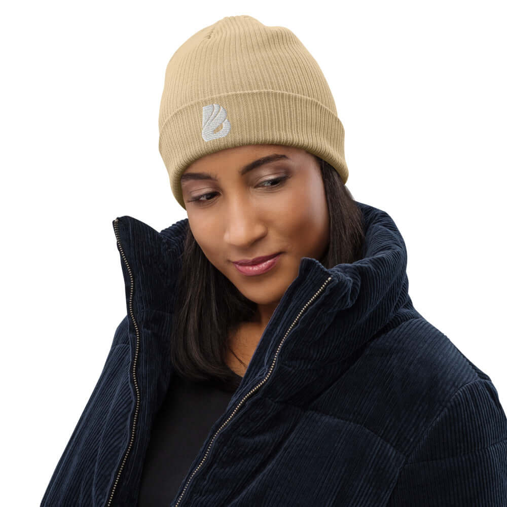 Gerippte Bio-Beanie N°0 in beige worn by a person in a navy jacket, highlighting eco-friendly style and comfort.