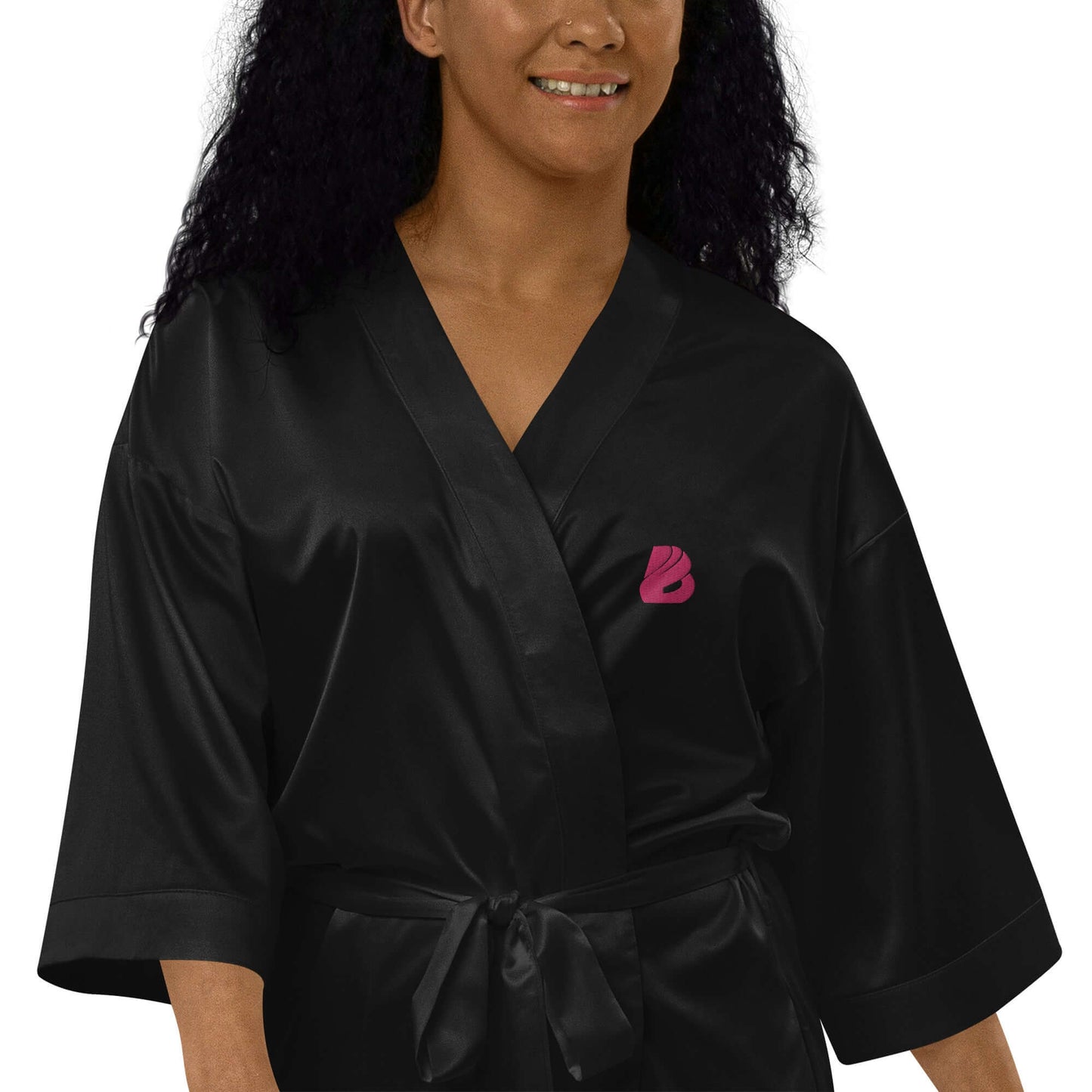 Woman wearing Satinmantel N°2 in black with pink logo detail, showcasing luxury kimono-style 3/4-sleeve satin robe.