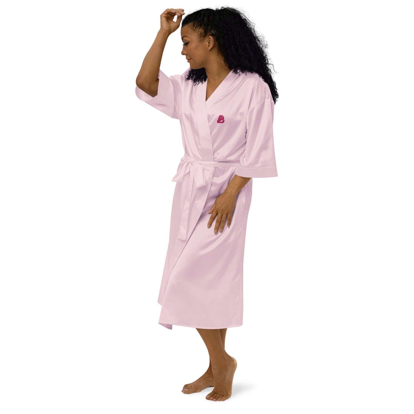 Woman wearing Satinmantel N°2 in pink, showcasing luxury kimono-style design and comfort.