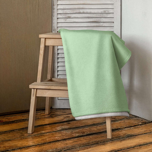 Handtuch N°0 in soft green draped over a wooden chair, adding a touch of elegance to any bathroom decor.