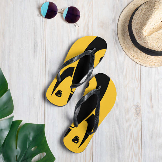 Flip-Flops N°6 in yellow and black design with Y-shaped black rubber straps on a wooden floor, styled with sunglasses and a hat.