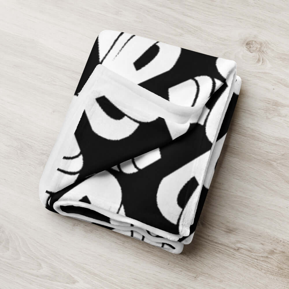 Folded black and white patterned Tagesdecke N°0 blanket, 100% polyester, soft silk-like fabric, hypoallergenic, machine washable.