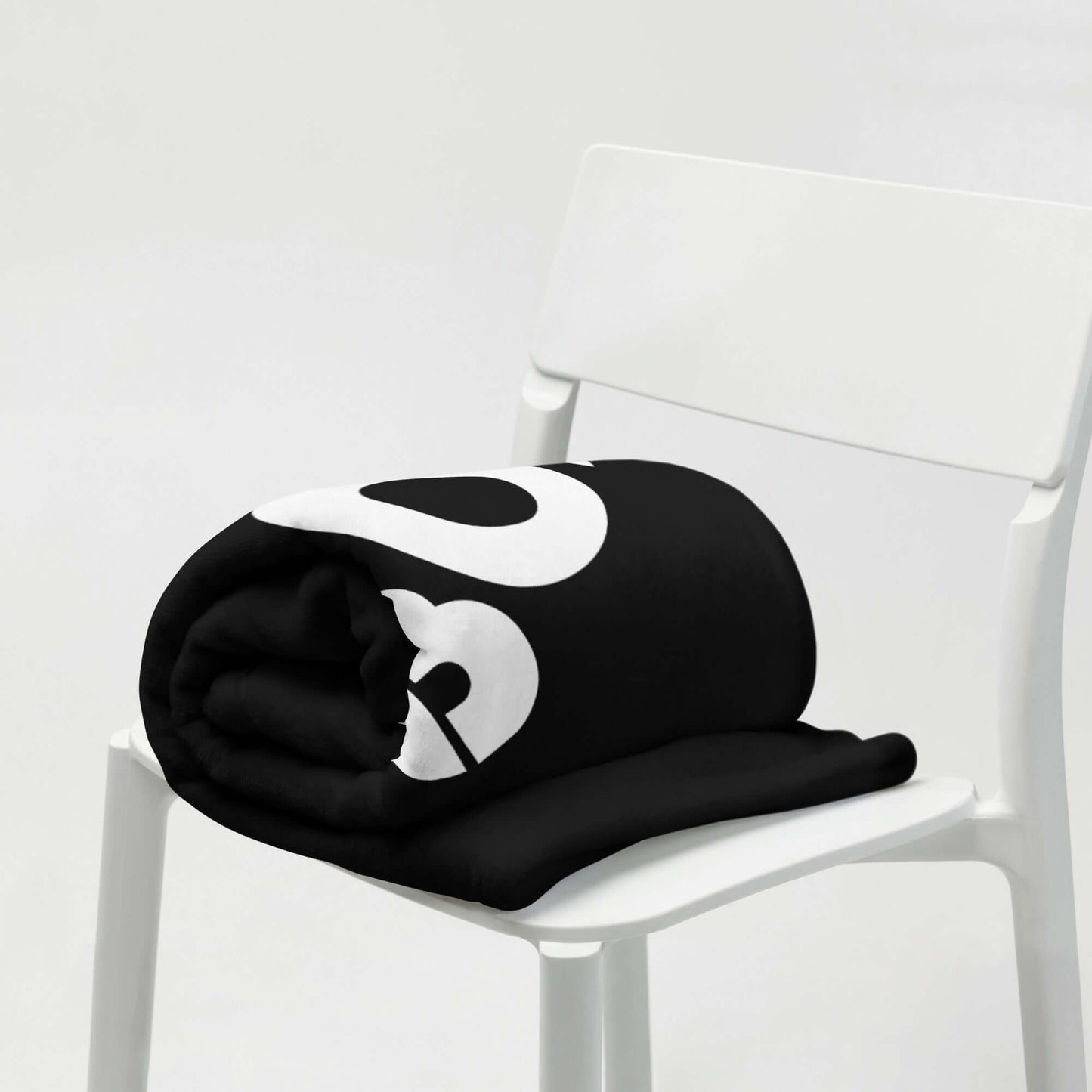 Schwarze Tagesdecke mit kreativem Druck auf einem weißen Stuhl, ideale Wohnkulturergänzung, hypoallergen und maschinenwaschbar.