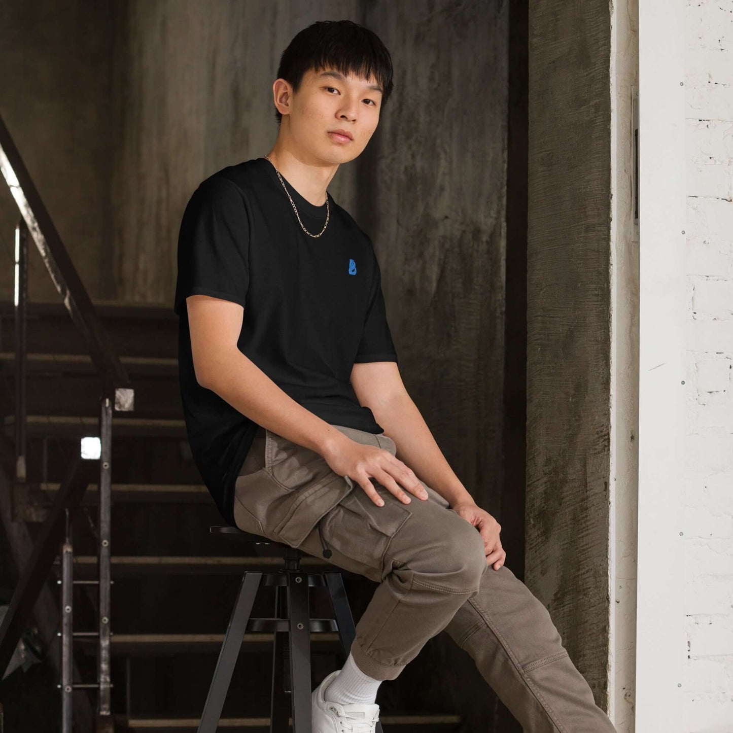 Kurzärmeliges Unisex-T-Shirt N°6 in black worn by model sitting on stool