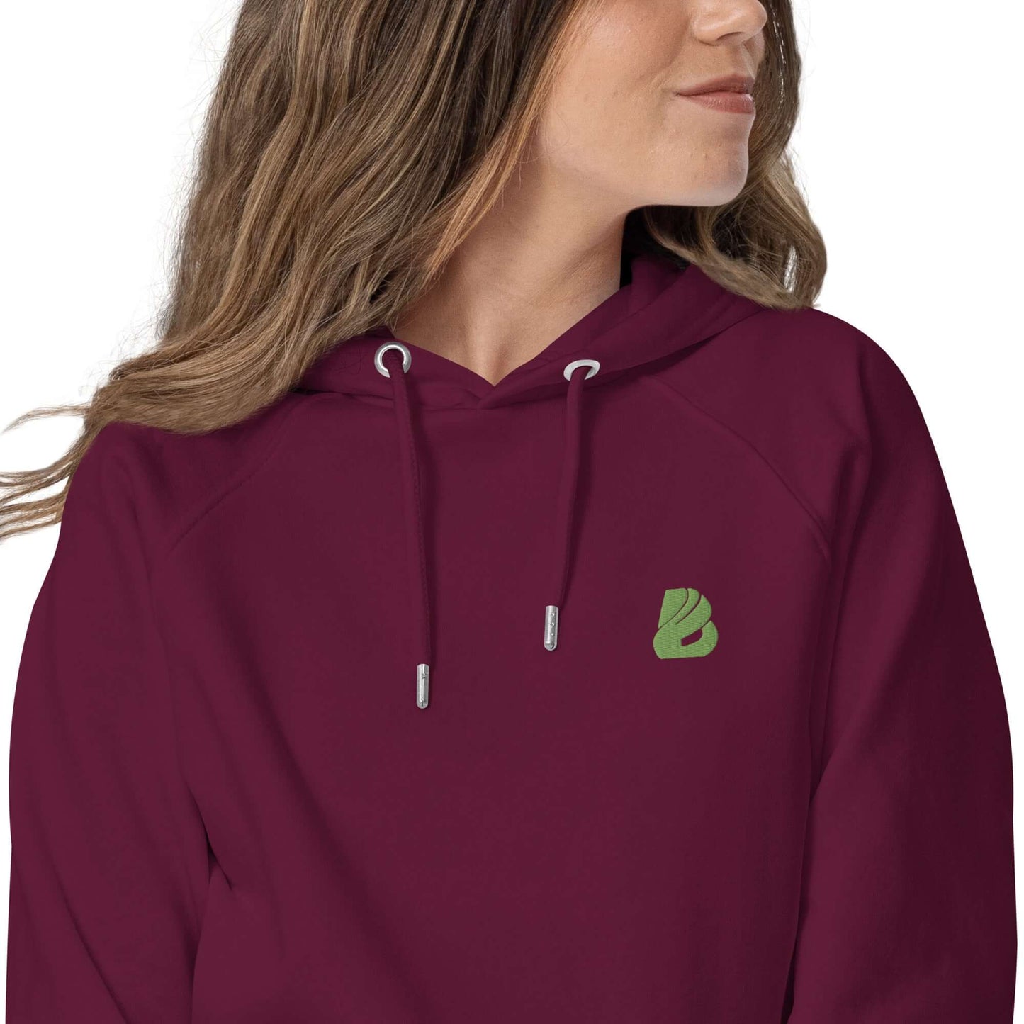 Woman wearing maroon Unisex Bio-Raglan-Hoodie N°0 with green logo, showcasing comfort and style.