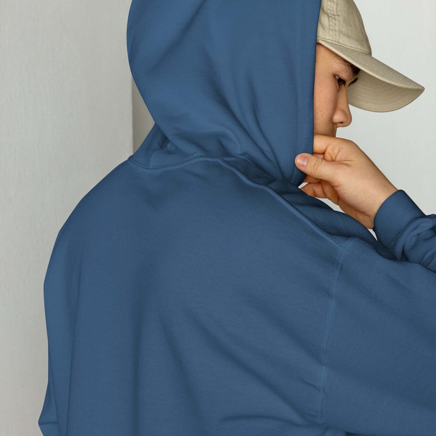 Model wearing Unisex-Kapuzenpullover N°46 in blue with beige cap.
