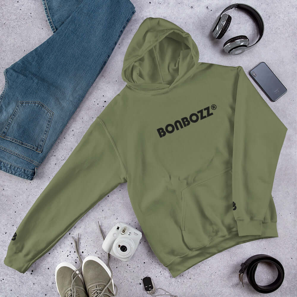 Unisex-Kapuzenpullover N°46 in olive green with cozy and stylish features, ideal for cool evenings, surrounded by jeans and accessories.