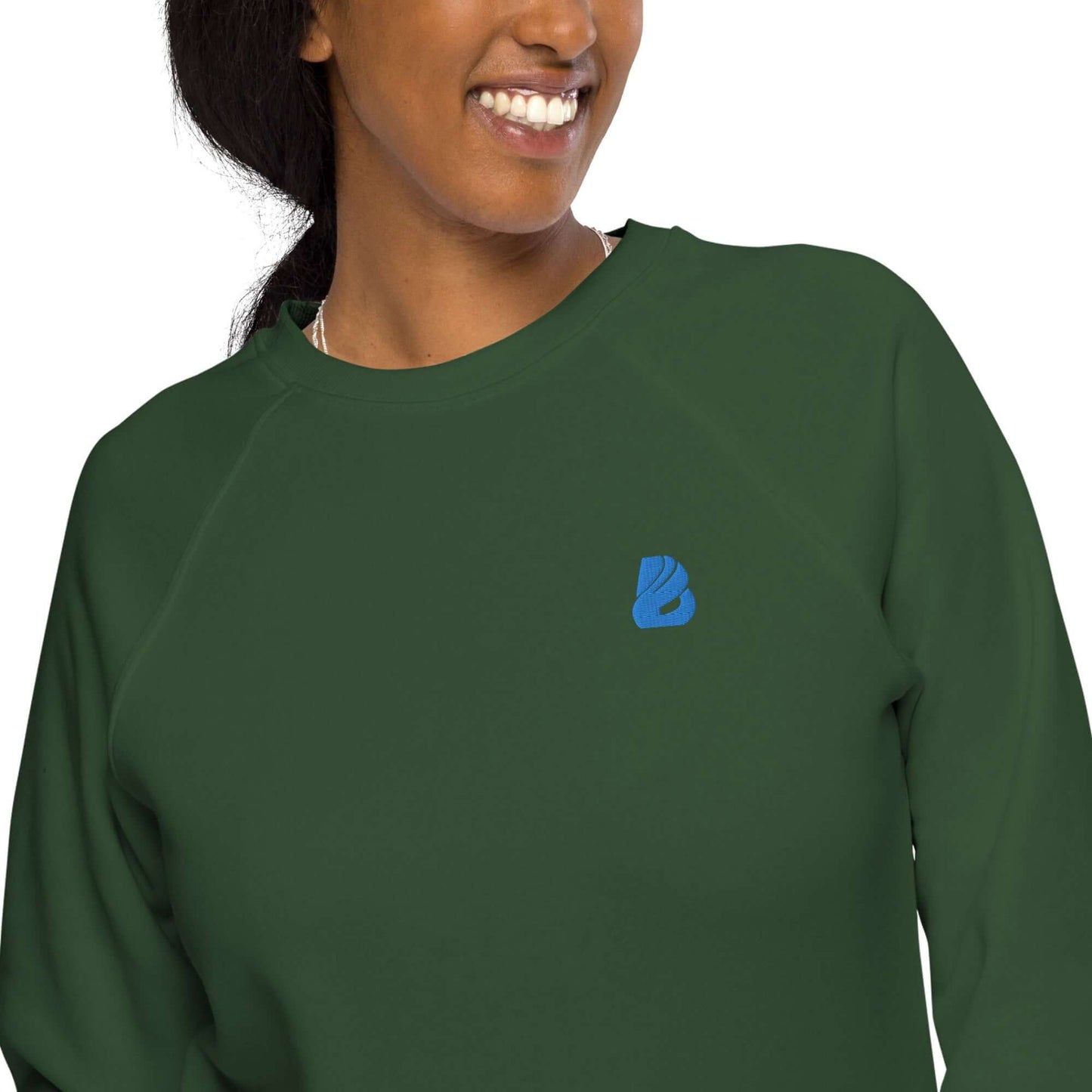 Person wearing Unisex Bio-Raglan-Pullover N°1 in green with blue logo, featuring soft fleece lining and 100% cotton exterior for comfort.
