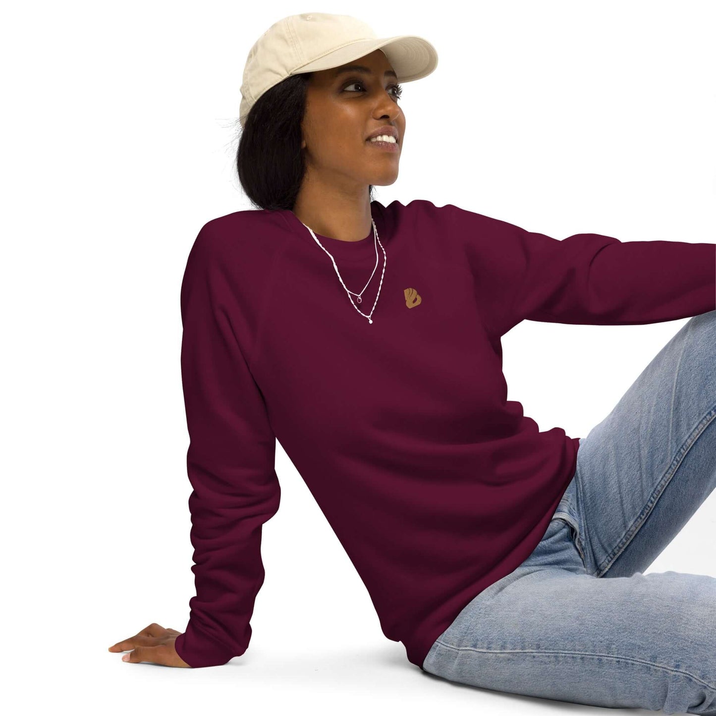 Unisex Bio-Raglan-Pullover N°0 in burgundy worn by a woman with a hat, showcasing comfort and style in 100% organic cotton.