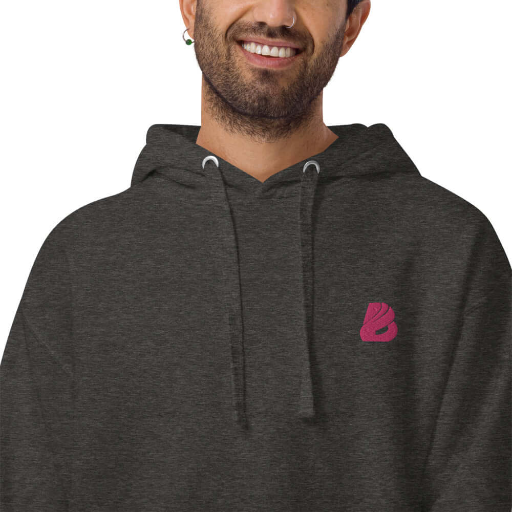 Person wearing Unisex-Kapuzenpullover N°22 with dark gray design and pink logo.