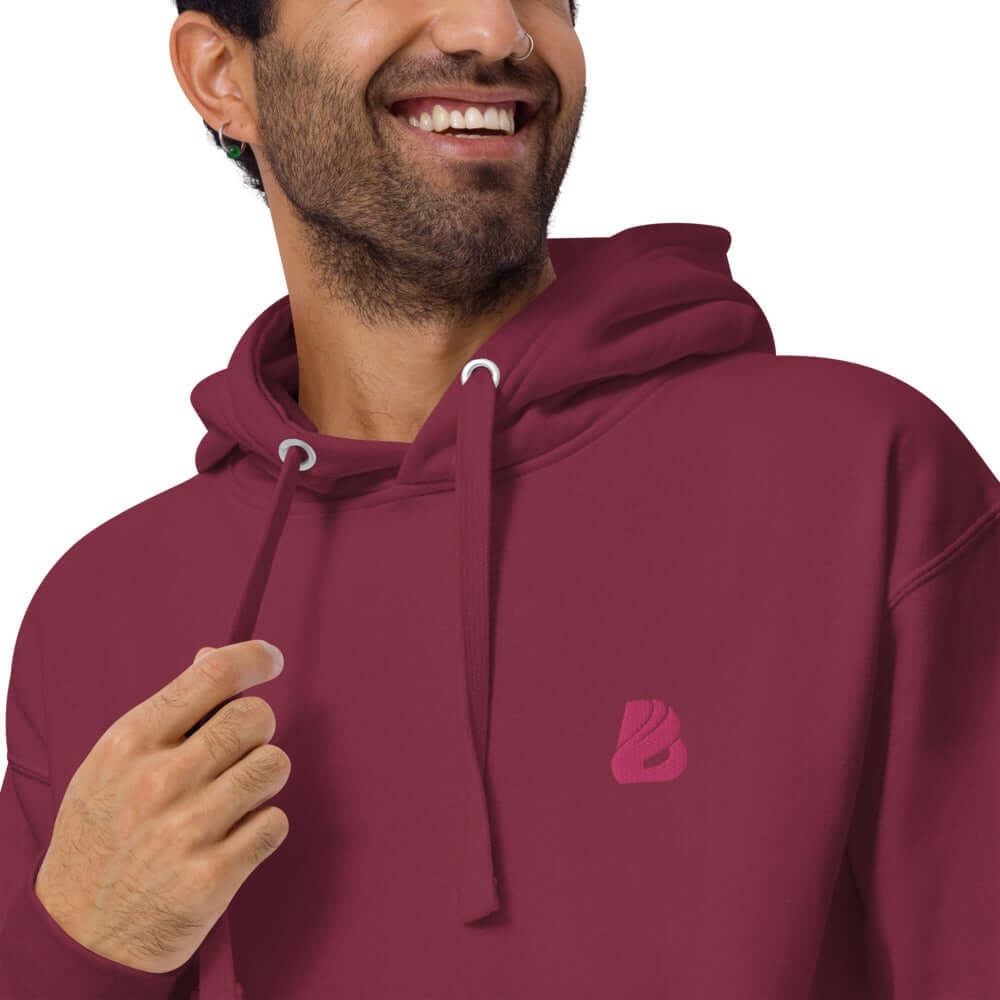 Unisex-Kapuzenpullover N°22 in burgundy worn by model with logo detail, soft fabric, kangaroo pocket, and hood for cool evenings.