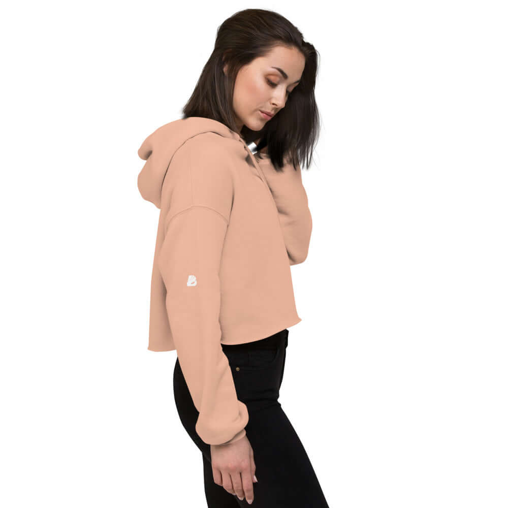 Woman wearing Crop-Hoodie N°0 in pink with raw hem and matching drawstring, showcasing side profile.
