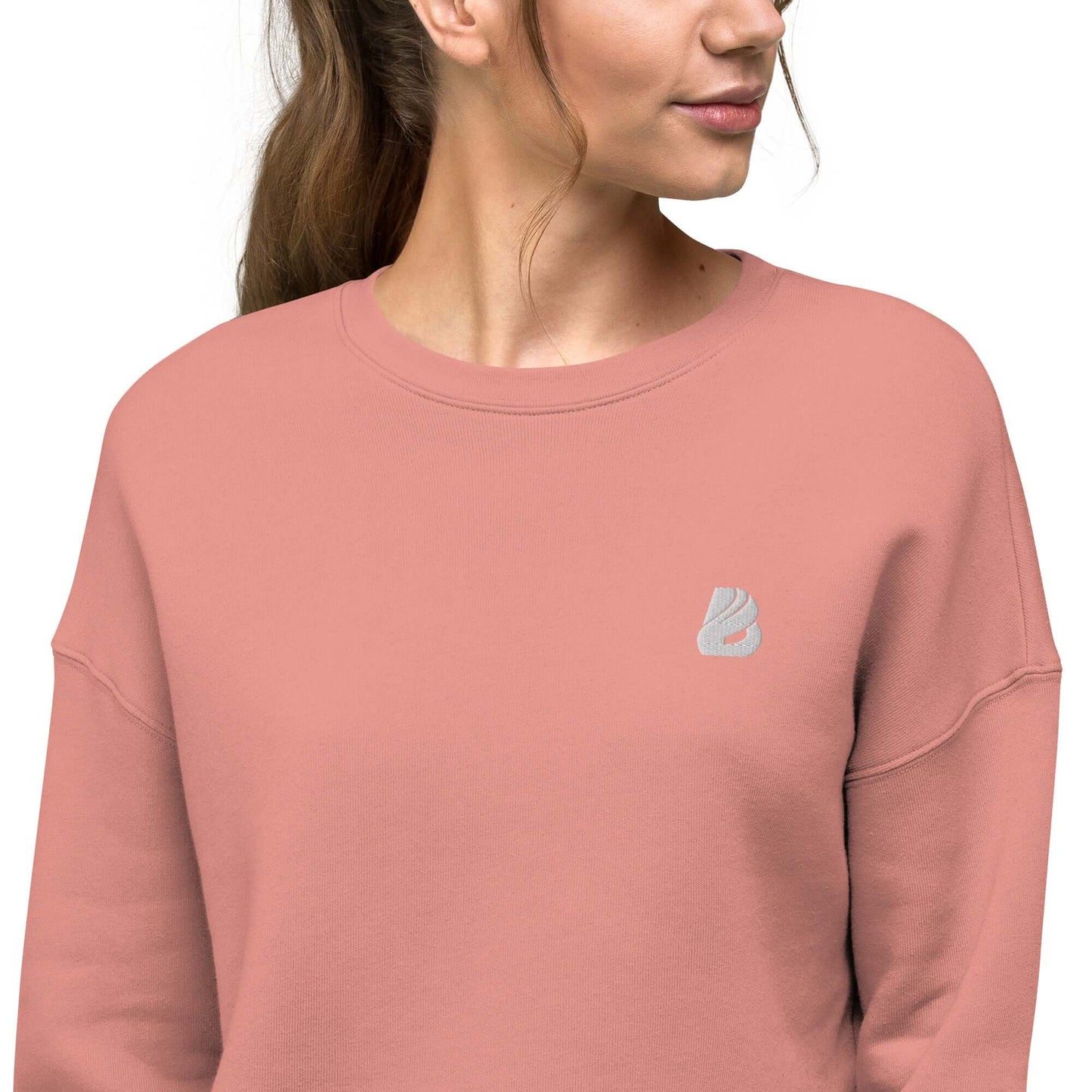 Woman wearing Crop-Pullover N°0, pink fleece fabric with ribbed neckline and raw hem, showcasing style and comfort.