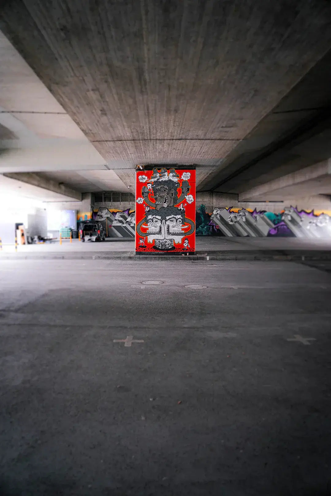 Colorful street art mural on a concrete wall beneath a bridge in an urban setting.