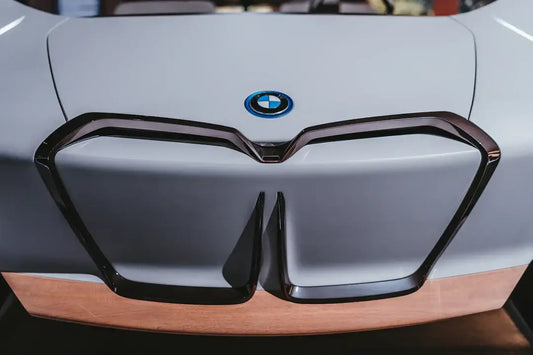 Close-up of a BMW logo on the front of a modern car with sleek design and wooden accents.