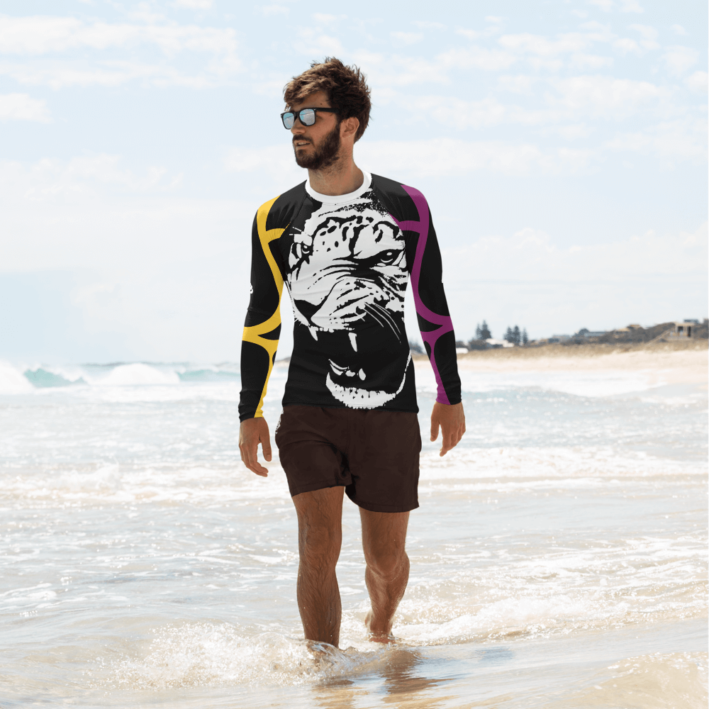 Stylish man in tiger-print rash guard walking on beach, showcasing summer casual fashion.