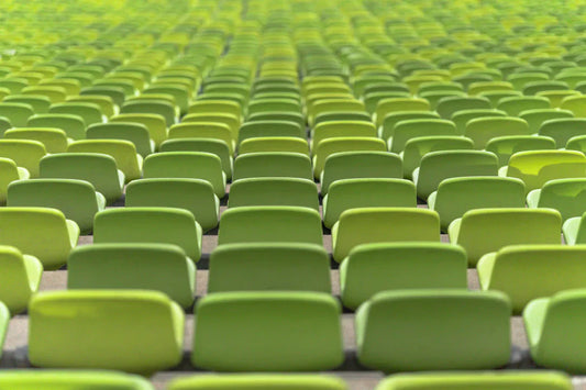 Repetitive pattern of green stadium seats arranged in rows, creating a vibrant and inviting scene.