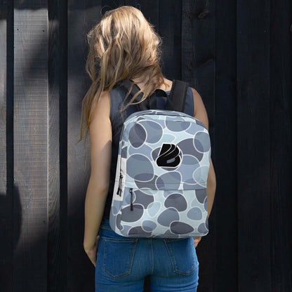Person wearing stylish Rucksack N°5 for daily or sports use, featuring ample storage and waterproof material, against a wooden background.