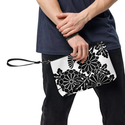 Person holding black and white floral Umhängetasche N°1 with detachable strap, made of high-quality faux leather.