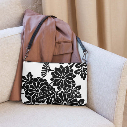 Black and white floral print Umhängetasche N°1 on beige sofa, featuring detachable strap and high-quality finishes