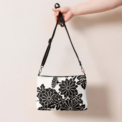Umhängetasche N°1 with floral pattern, adjustable strap, and black hardware, hand-held against a neutral background.