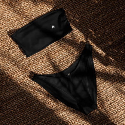 Recycelter Bandeau-Bikini mit Allover-Druck, schwarz, auf einem natürlichen Hintergrund, ideal für Strand und Pool.