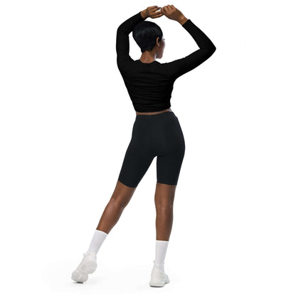 Back view of model wearing Recyceltes Langarm Crop Top mit Allover-Druck N°3 in black, paired with cycling shorts and white socks.