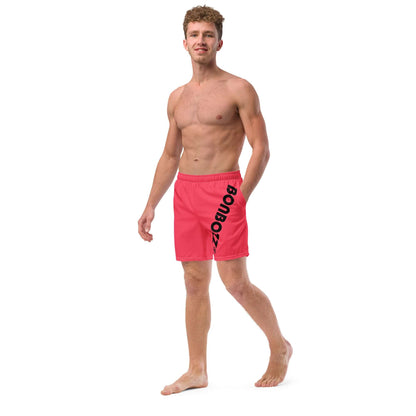 Model wearing Herren-Badehosen N°13, red swim shorts with black logo, featuring quick-dry and breathable fabric.